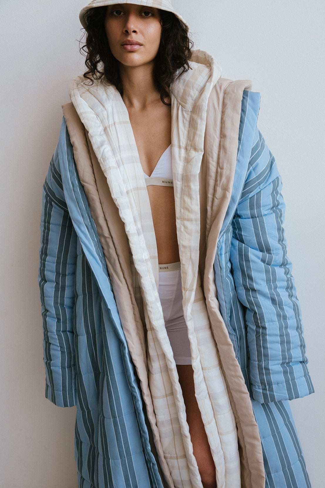 Long Doona Robes in Daybreak Stripe, Oat and Oat Check worn layered over white women's boxer briefs and triangle bralette by female model also wearing Oat Check Doona Hat.