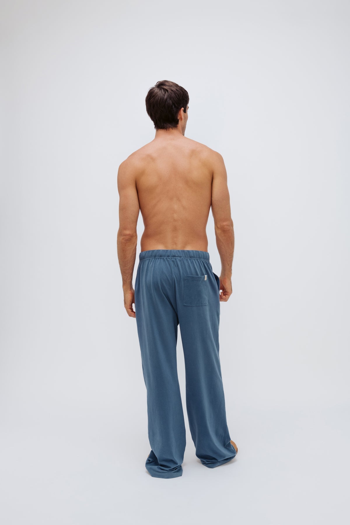 Cosy Pant in Noon worn by male model, back view showing back pocket