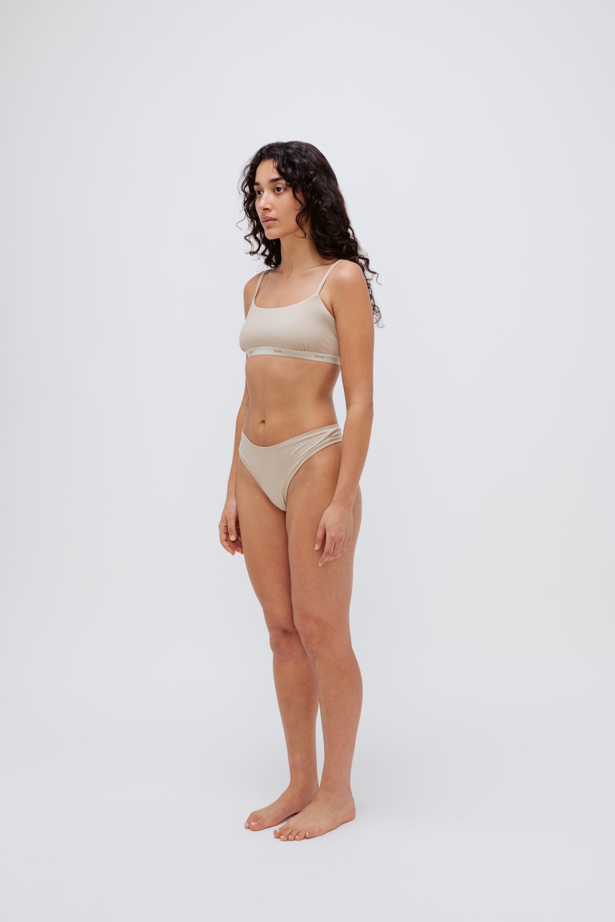 Square Neck Bralette in latte silky-soft micromodal blend worn with women's latte g string by female model, front view showing softly structured silhouette and NUNE soft elastic on bralette.