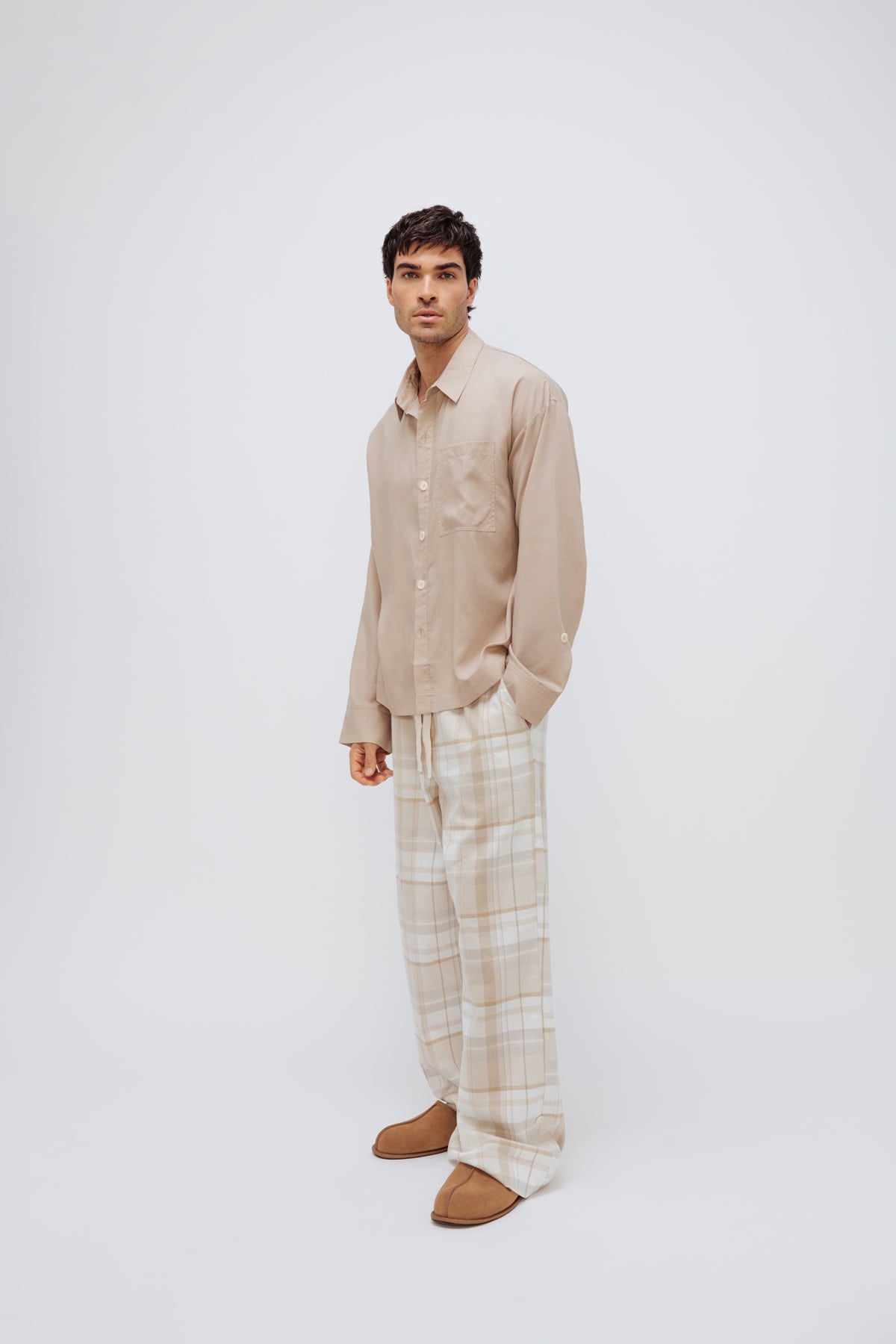 Oat long sleeve sleep shirt and flannel sleep pant in Oat Check being worn by male model, front side view showing front pocket on pants and adjustable sleeve length on shirt.