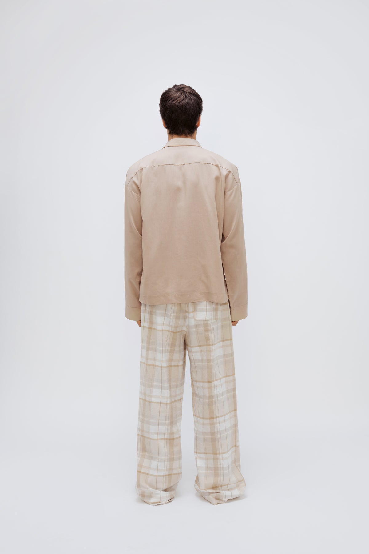 Oat long sleeve sleep shirt and flannel sleep pant in Oat Check being worn by male model, back view showing back pocket on pants.