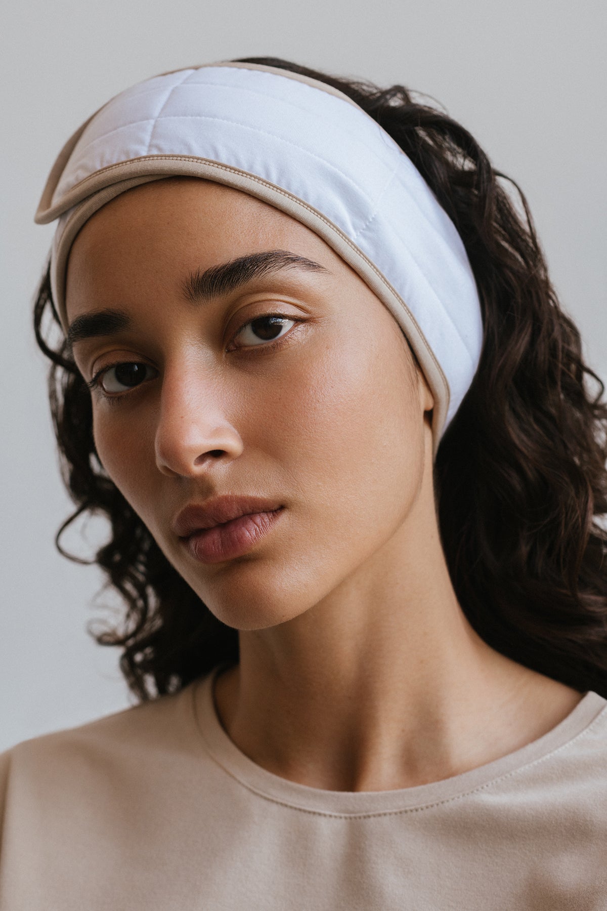 White soft padded spa skin care headband with velcro adjustable closure worn by female model close up view
