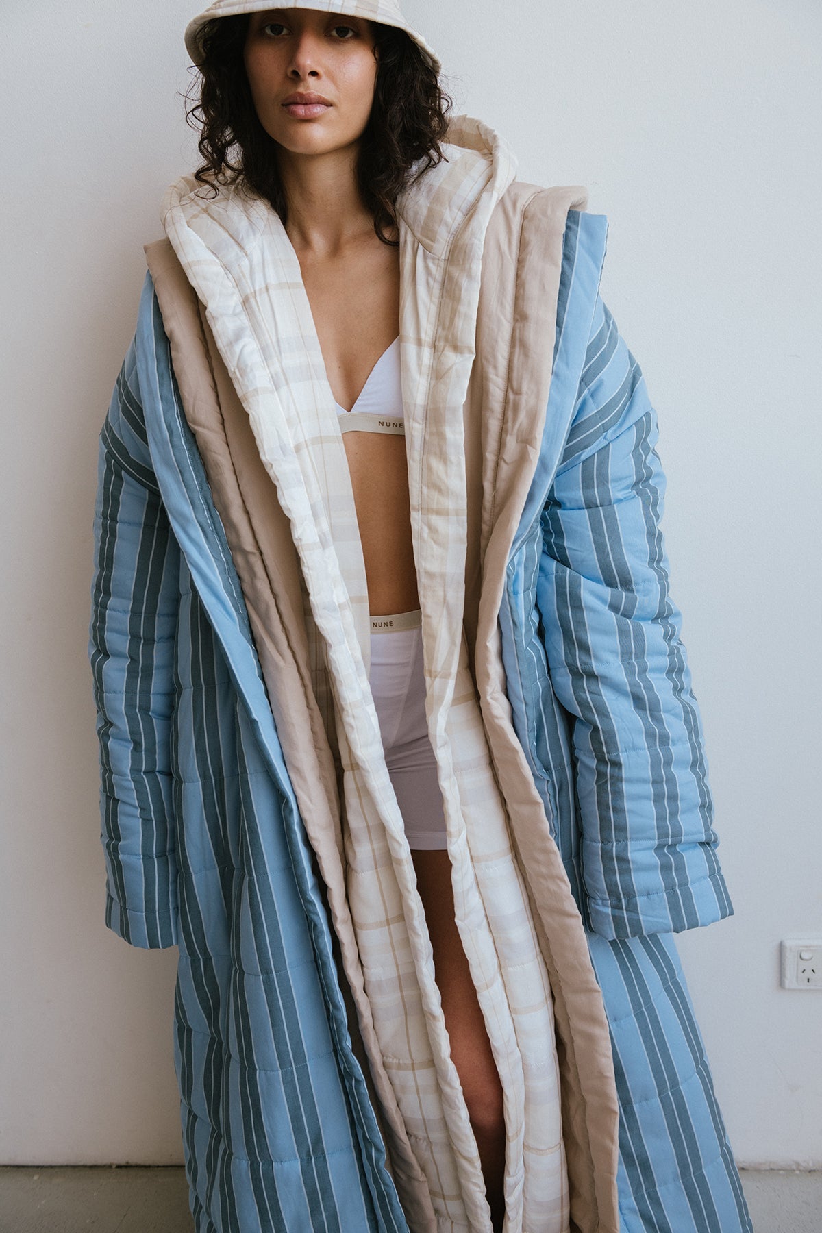 Long Doona Robes in Daybreak Stripe, Oat and Oat Check worn layered over white women's boxer briefs and triangle bralette by female model also wearing Oat Check Doona Hat.