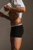 White Oversized Tee with a drop-shoulder silhouette made in organic cotton jersey and Black Original Boxer Briefs worn by male model, cropped side view