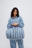 Doona Tote in Daybreak Stripe held by female model in front of her body, wearing Long Sleeve Sleep Shirt and Long Sleep Pants Flannel in Daybreak Stripe