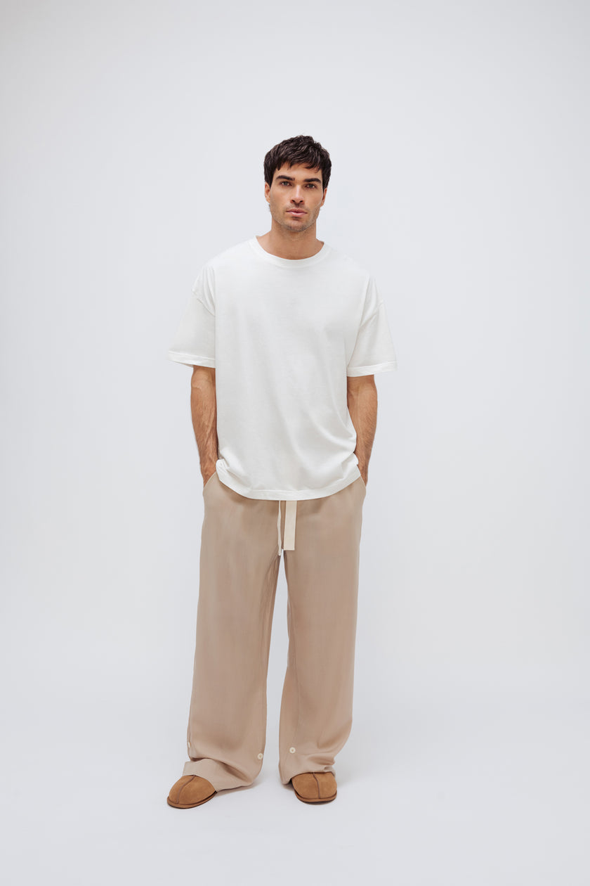 White Oversized Tee with a drop-shoulder silhouette made in organic cotton jersey and Oat Long Sleep Pant Macel worn by male model, front view