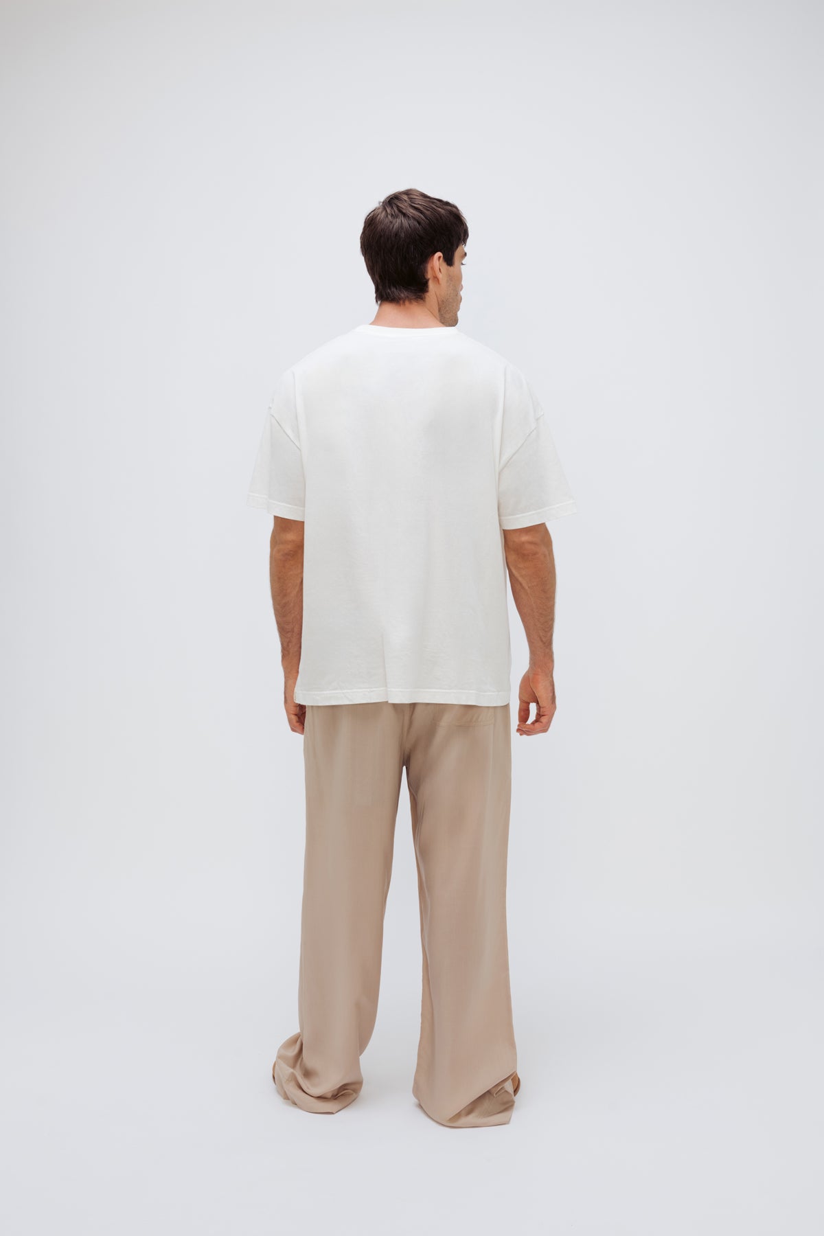 White Oversized Tee with a drop-shoulder silhouette made in organic cotton jersey and Oat Long Sleep Pant Macel worn by male model, back view