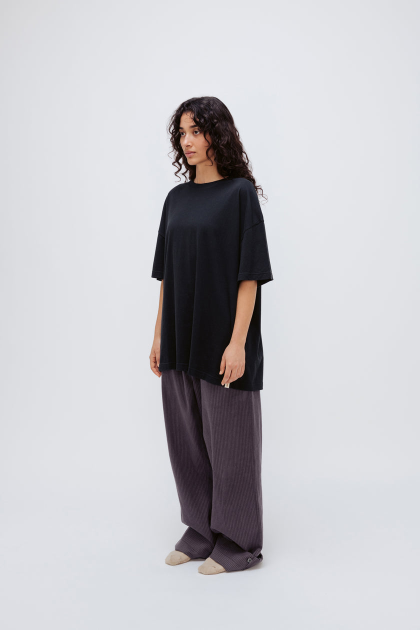 Black Oversized Tee in soft organic cotton jersey and Long Sleep Pant Flannel in Evening Pinstripe worn by female model, front side view
