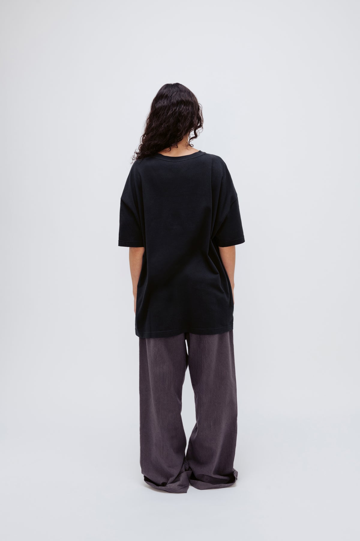 Black Oversized Tee in soft organic cotton jersey and Long Sleep Pant Flannel in Evening Pinstripe worn by female model, back view