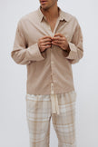 Long sleeve sleep shirt in Oat and flannel sleep pant in Oat Check being worn by male model, cropped mid-section front view showing button fastenings down front of shirt and natural cotton waist tie on pants. 