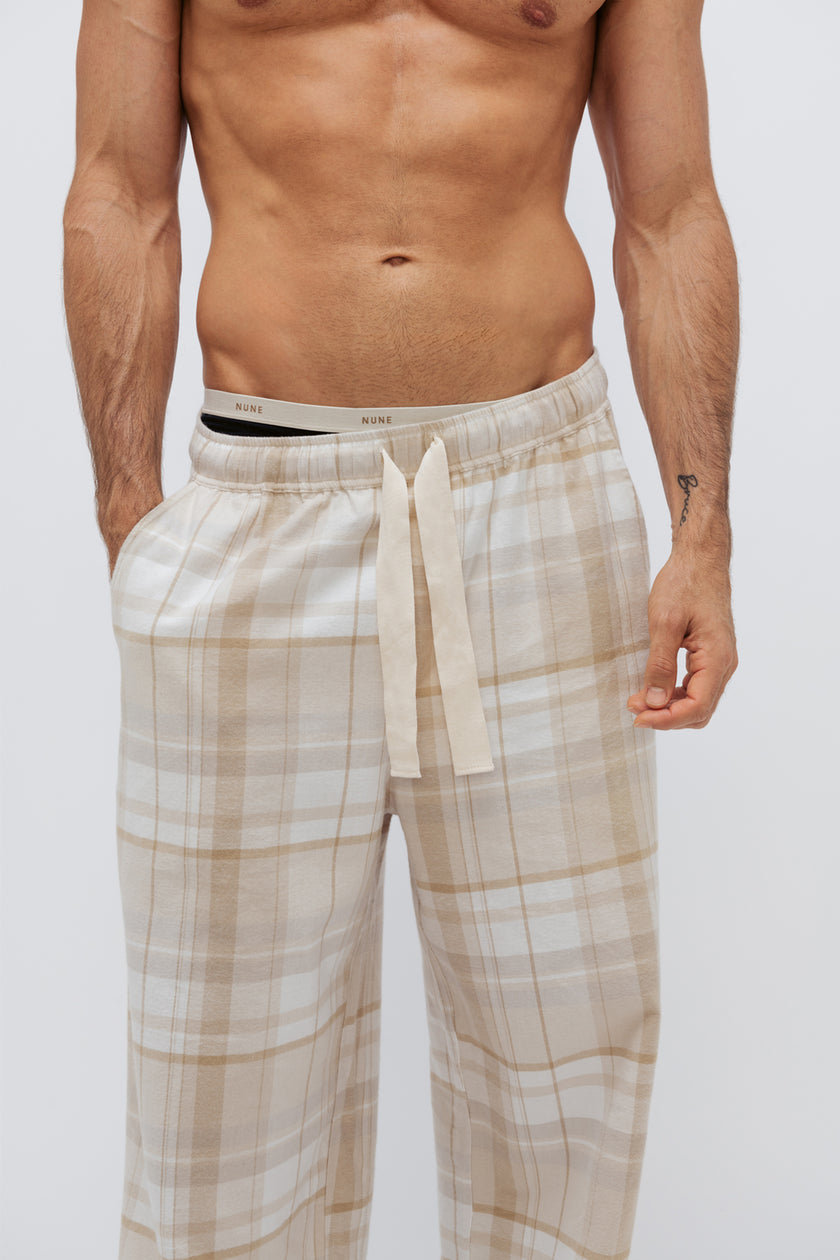 Flannel sleep pant in Oat Check being worn by male model over Men's original boxer briefs in black, cropped front side view showing NUNE soft elastic on briefs and natural cotton waist tie on pants. 
