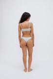 Triangle Bralette in daybreak silky-soft micromodal blend worn with women's daybreak g string by female model, back view showing adjustable straps and NUNE soft elastic on bralette.