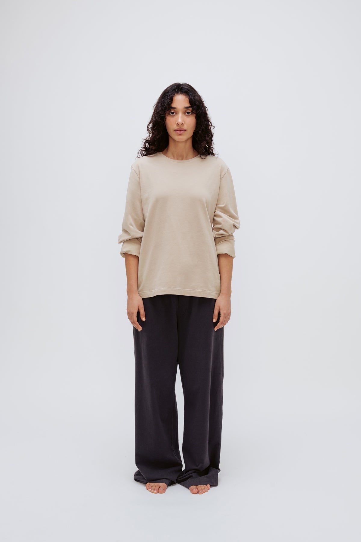 Cosy Long Sleeve Top in Latte and Cosy Pants in Charcoal worn by female model front view with sleeves rolled up on arms