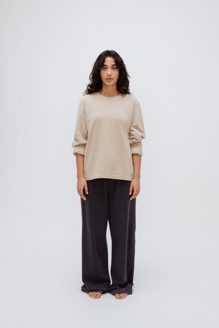 Cosy Long Sleeve Top in Latte and Cosy Pants in Charcoal worn by female model front view with sleeves rolled up on arms