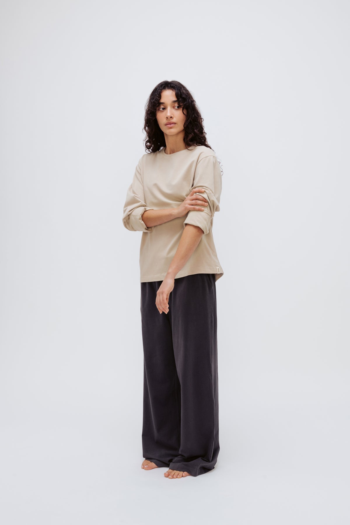 Cosy Long Sleeve Top in Latte and Cosy Pants in Charcoal worn by female model front side view with sleeves rolled up on arms