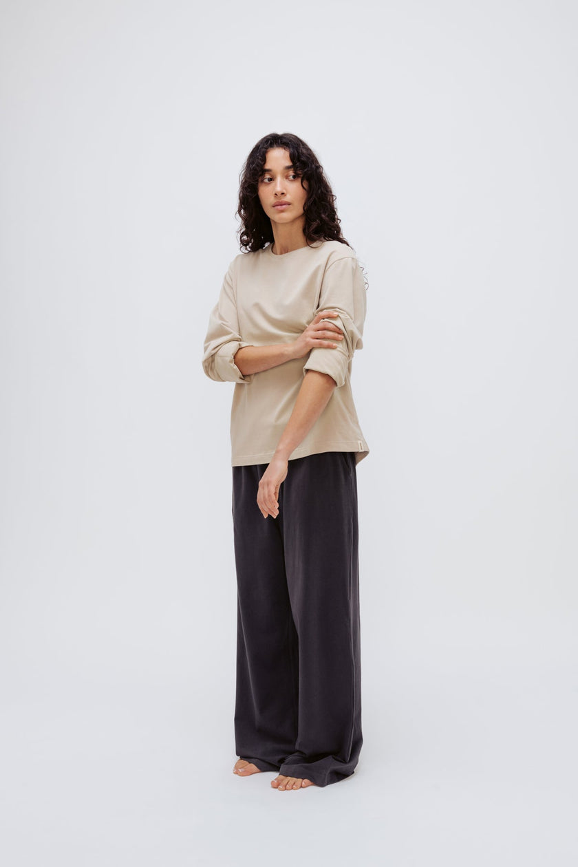 Cosy Long Sleeve Top in Latte and Cosy Pants in Charcoal worn by female model front side view with sleeves rolled up on arms
