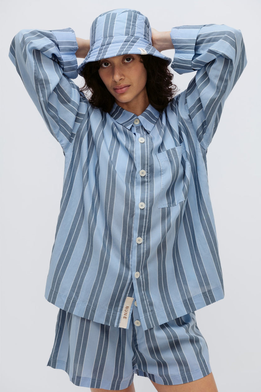 Long Sleeve Sleep Shirt Macel, Boxer Short and Doona Hat all in Daybreak Stripe worn by female model holding her hands behind her head, cropped front view.