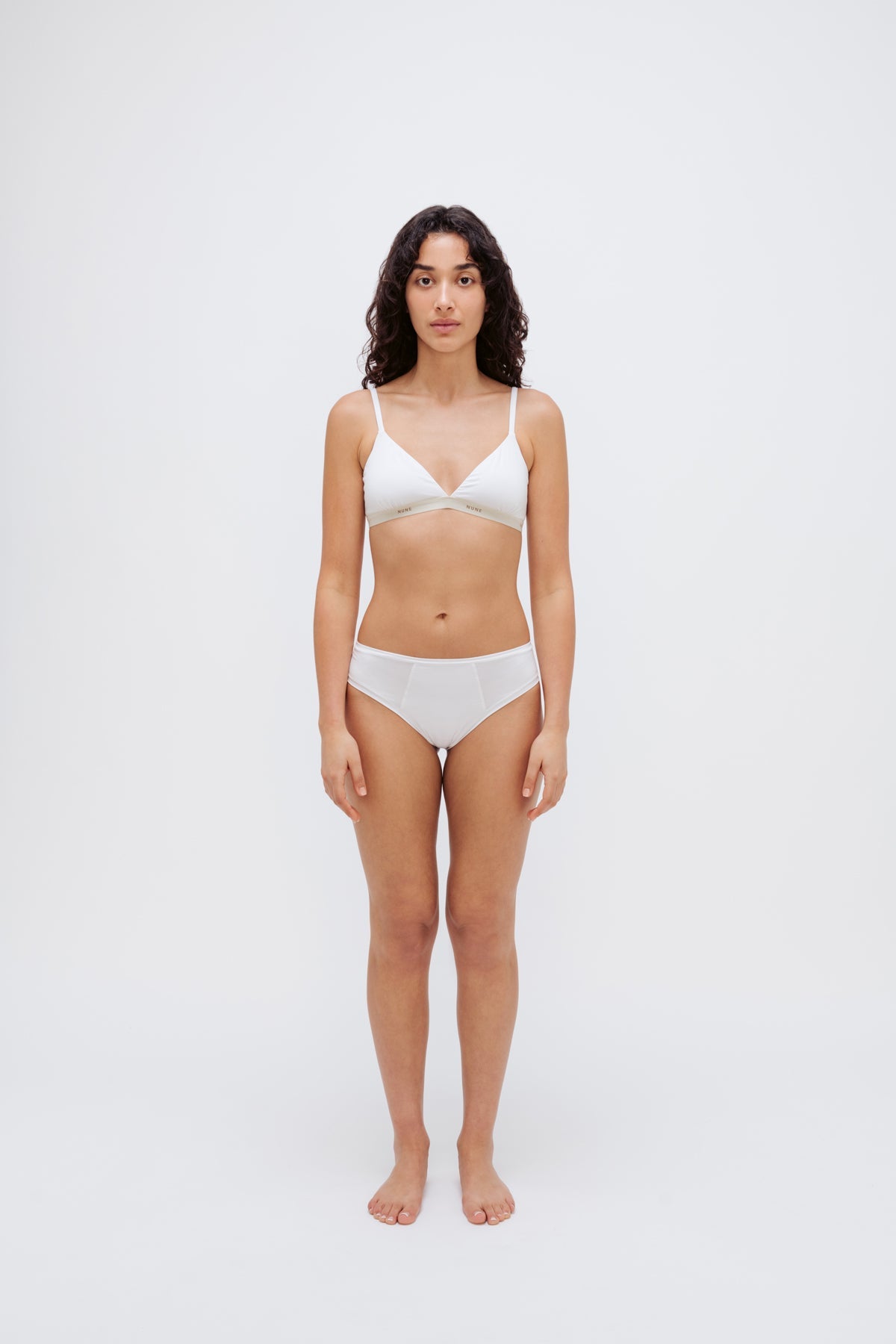 White triangle bralette and white mid brief worn by female model, front view showing flattering low neckline on bralette and double-lined front on briefs.