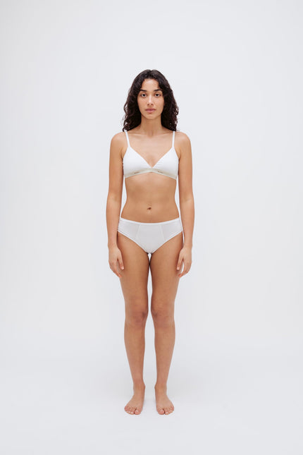 White triangle bralette and white mid brief worn by female model, front view showing flattering low neckline on bralette and double-lined front on briefs.