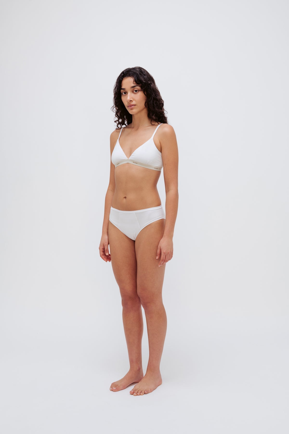 White triangle bralette and white mid brief worn by female model, front side view showing flattering low neckline on bralette and double-lined front on briefs.
