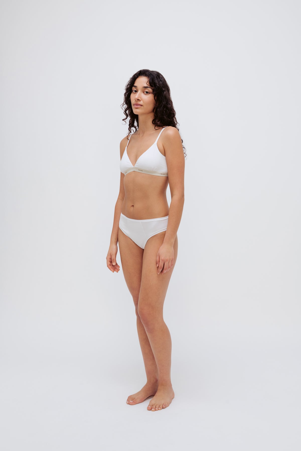 White triangle bralette and white mid brief worn by female model, front side view showing flattering low neckline on bralette and double-lined front on briefs.