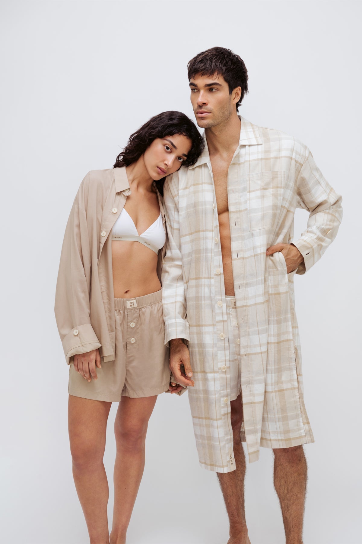Oat boxer shorts and sleep shirt worn by female model over white triangle bralette and oat check boxer shorts and long house shirt worn by male model both facing front