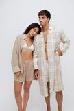 Oat boxer shorts and sleep shirt worn by female model over white triangle bralette and oat check boxer shorts and long house shirt worn by male model both facing front
