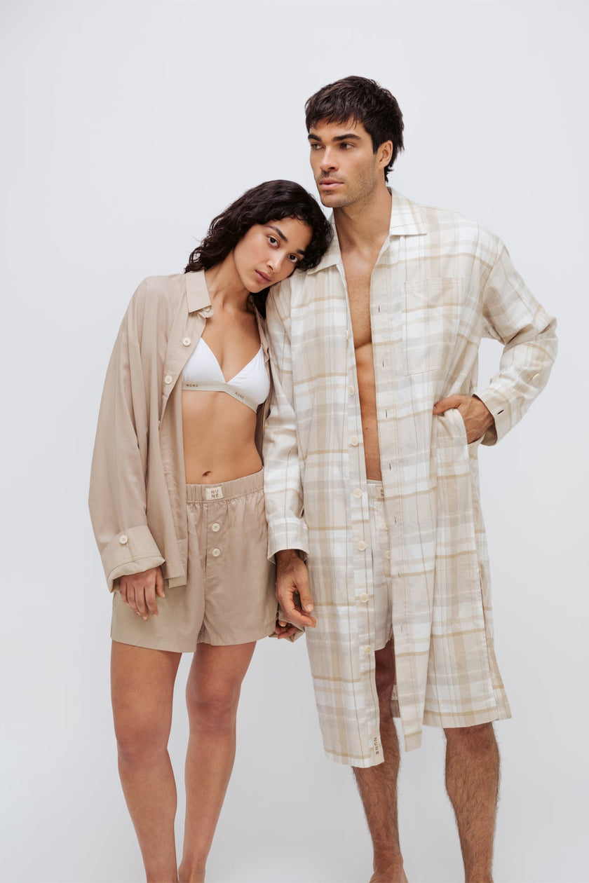 Oat boxer shorts and sleep shirt worn by female model over white triangle bralette and oat check boxer shorts and long house shirt worn by male model both facing front