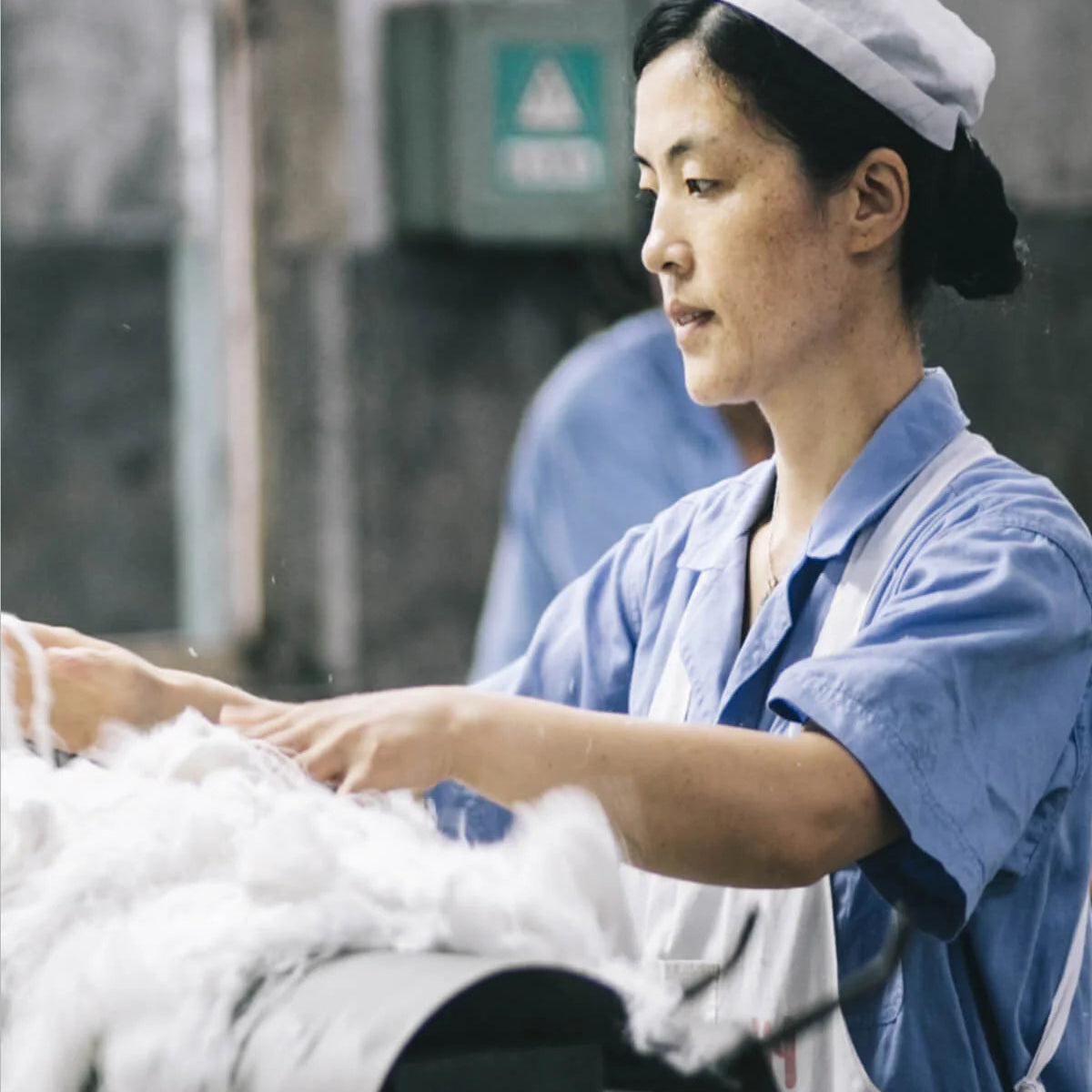 Person working with white fabric in a textile setting